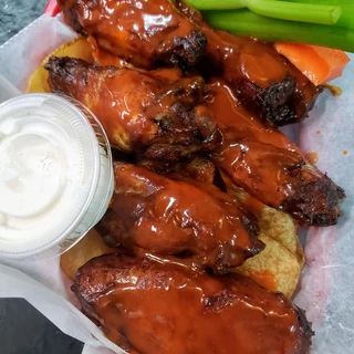 Saucy chicken wings served with celery, carrots, and a side of dip